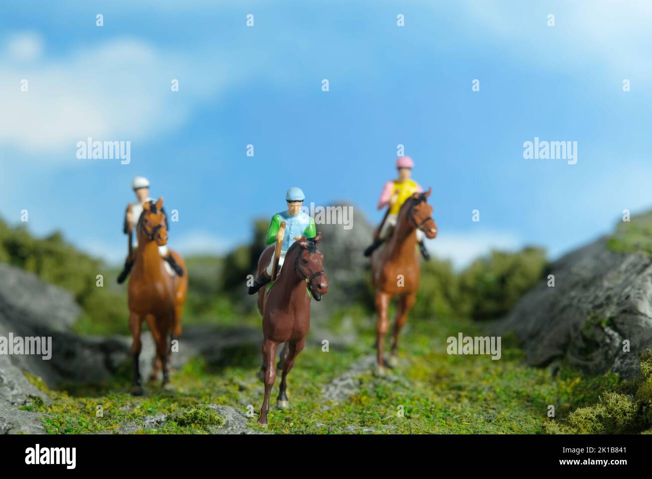 Miniature people toy figure photography. A jockey man riding horse at mountain hill for training. Image photo Stock Photo