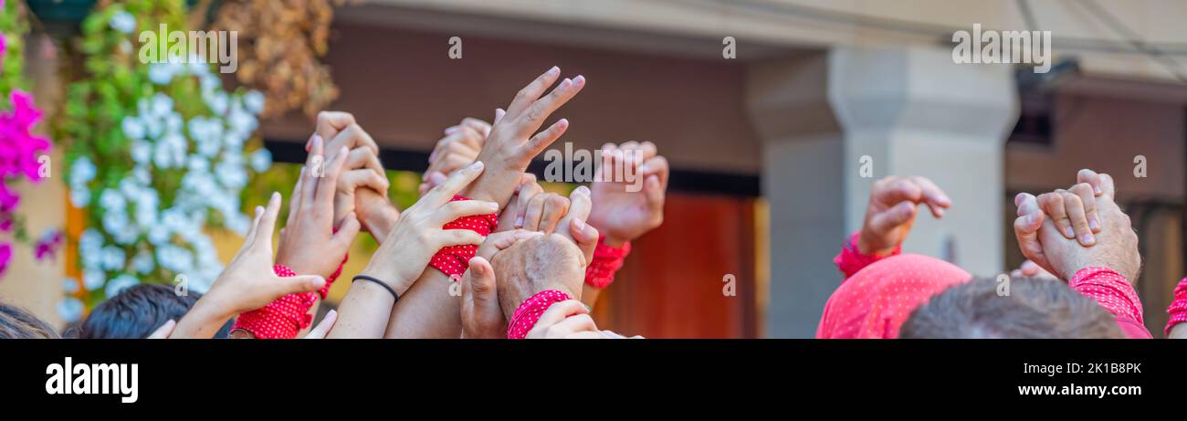CAMBRILS, SPAIN - SEPTEMBER 04.2022: Hands at a Castells Performance, a castell is a human tower built traditionally in festivals, panorama Stock Photo