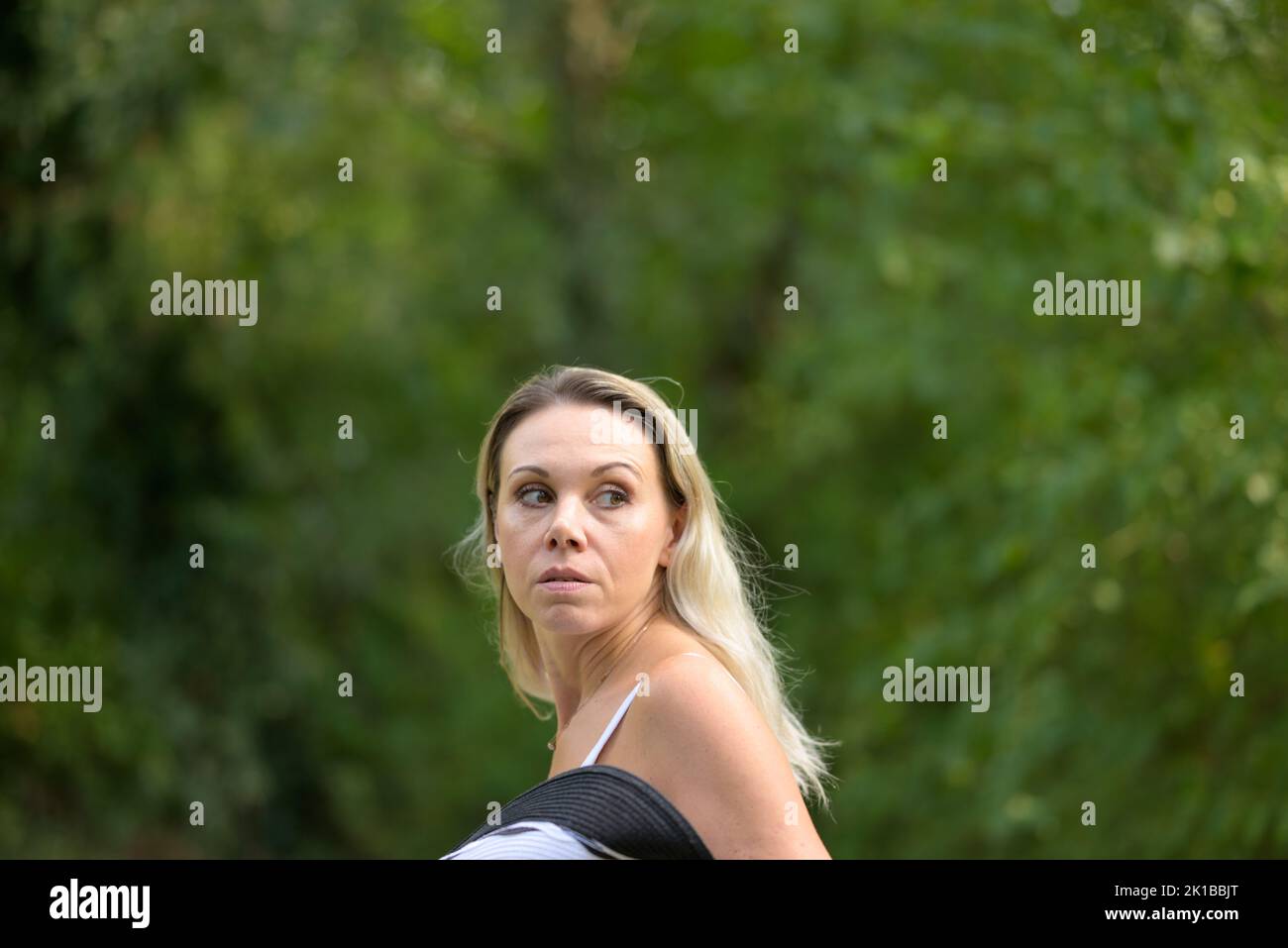 Attractive blond woman with a haunted expression, turns around and feels followed Stock Photo