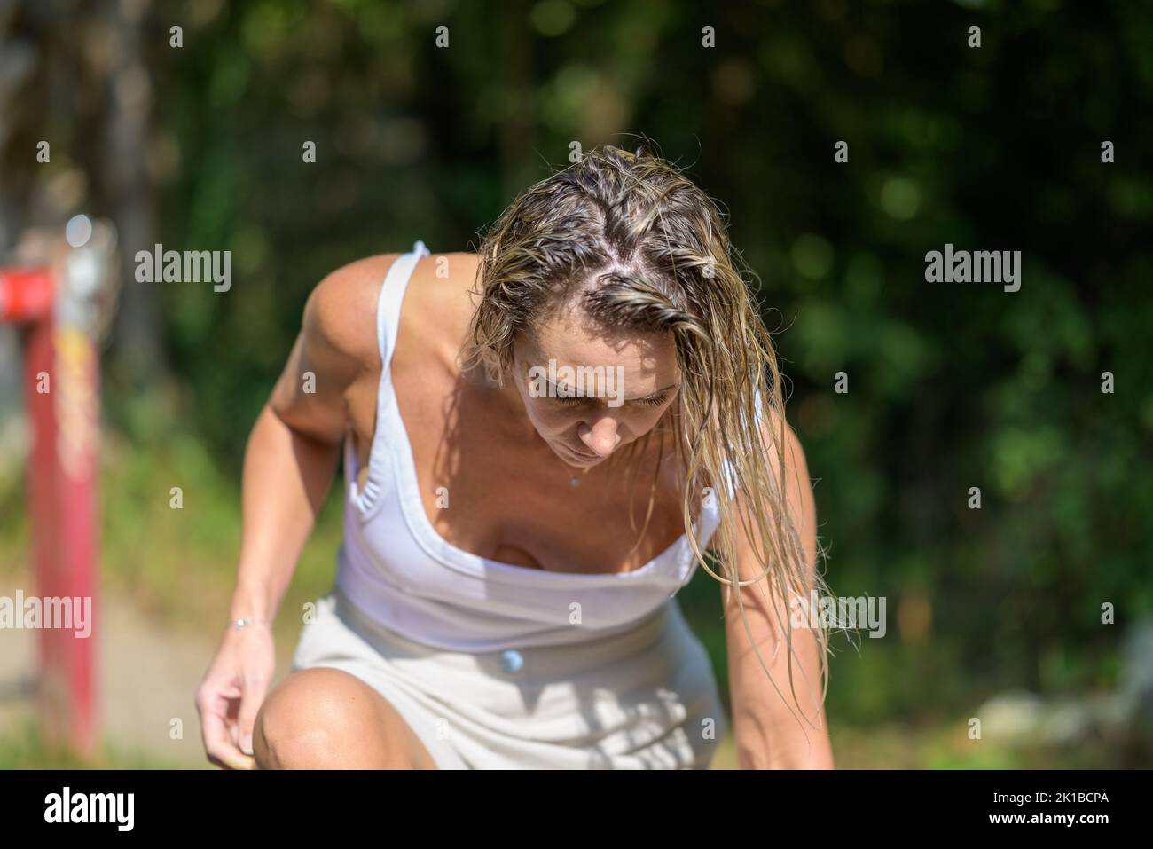 Blonde woman with wet hair leans forward and puts on her shoes Stock Photo