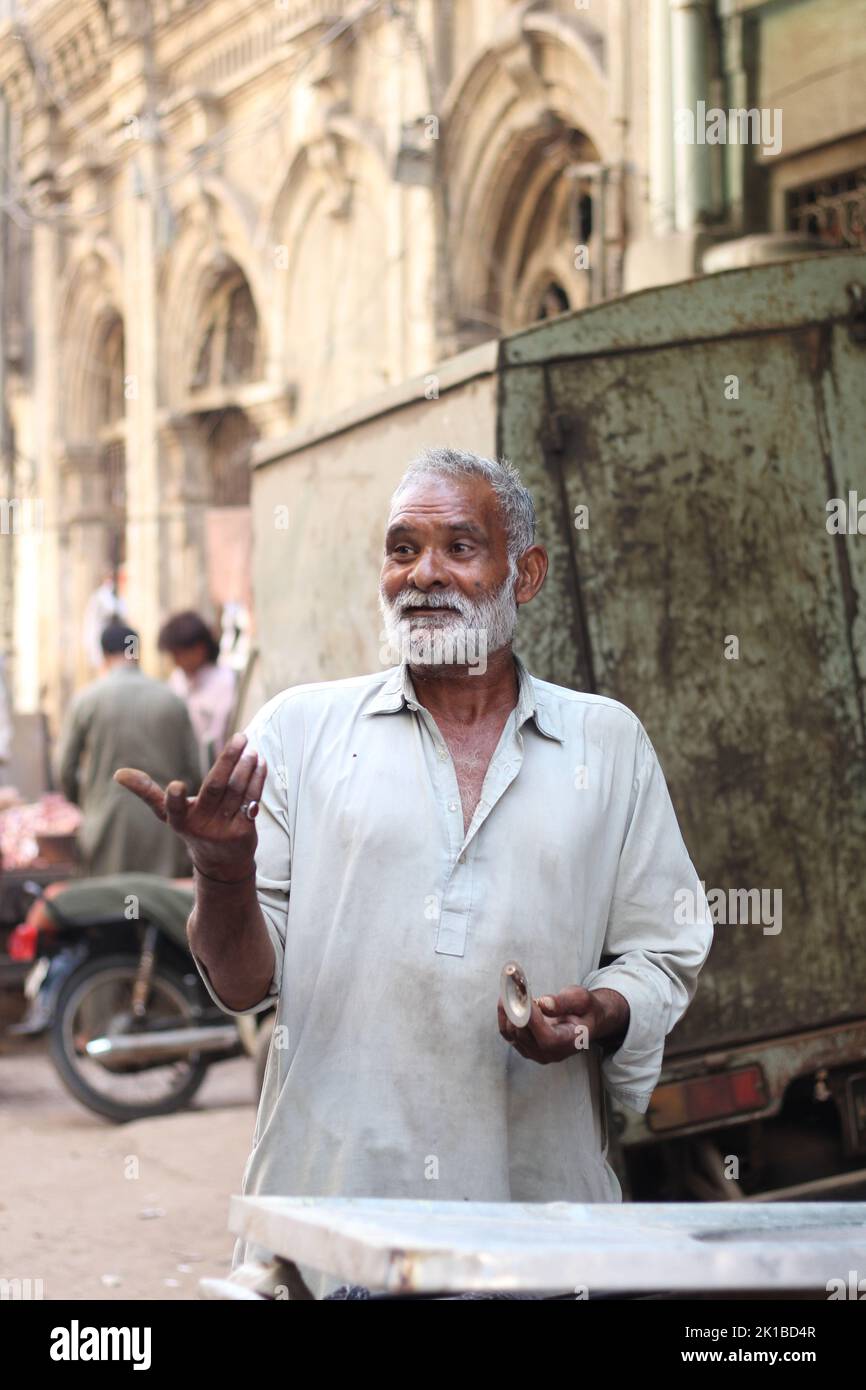 A vertical shot of a Pakistani old male with a white beard in a kurta on the street Stock Photo
