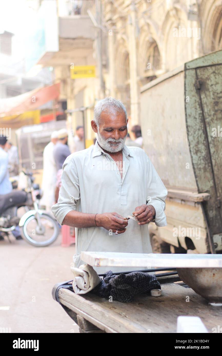 A vertical shot of a Pakistani old male with a white beard in a kurta on the street Stock Photo