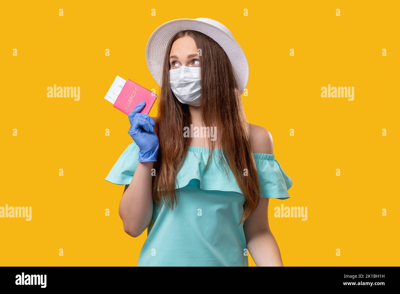 Pandemic tourism. Summer holidays. Woman in protective face mask gloves holding passport flight ticket isolated on orange copy space. Visa application Stock Photo