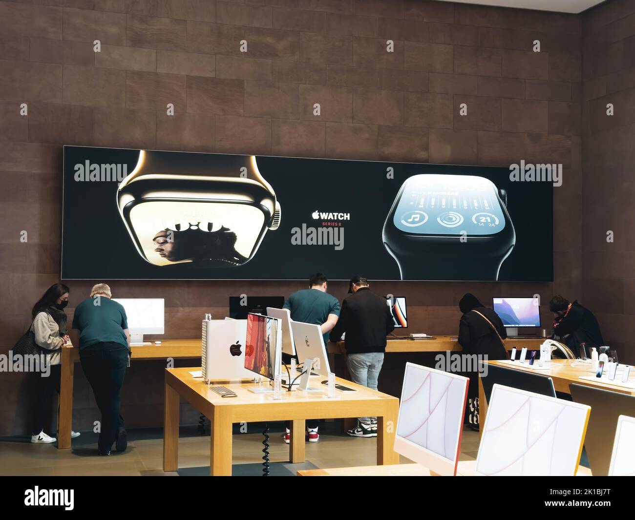 Paris, France - Sep 16, 2022: Busy crowd inspecting new Apple iMac computers with large advertising OOH for the new Watch series 8 with features: Cycle Tracking and Crash Detection two new temperature sensors, a high-g accelerometer, improved gyroscope. Stock Photo