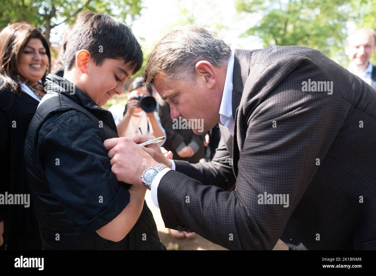 Langenselbold, Germany. 17th Sep, 2022. Boris Rhein (CDU, r), Minister President of Hesse, corrects the name of Mert, whose name tag was misspelled, with a pen during the triplet meeting at Langenselbold Castle. For more than two decades, the Minister President of Hesse has taken on the honorary sponsorships for multiple births starting with triplets in Hesse. Credit: Sebastian Gollnow/dpa/Alamy Live News Stock Photo