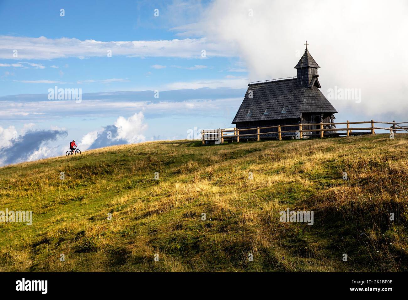 A Mountain biker on a  cycling trip to the wooden Chapel of Mary of the Snows on Velika Planina plateau near Kamnik, Slovenia Stock Photo
