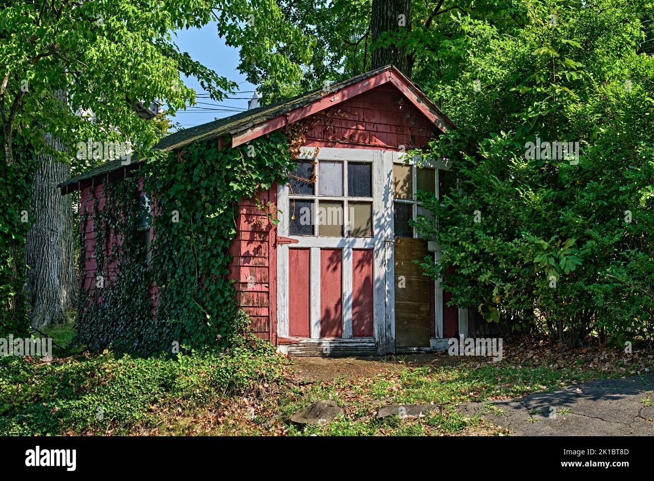 A cute old red vintage car garage in the 1940's style. With ivy growing up one side. Stock Photo