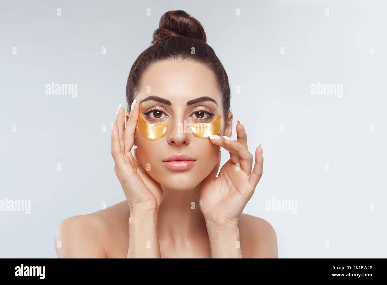 Woman applying golden eye patches. Close up portrait girl. Young woman