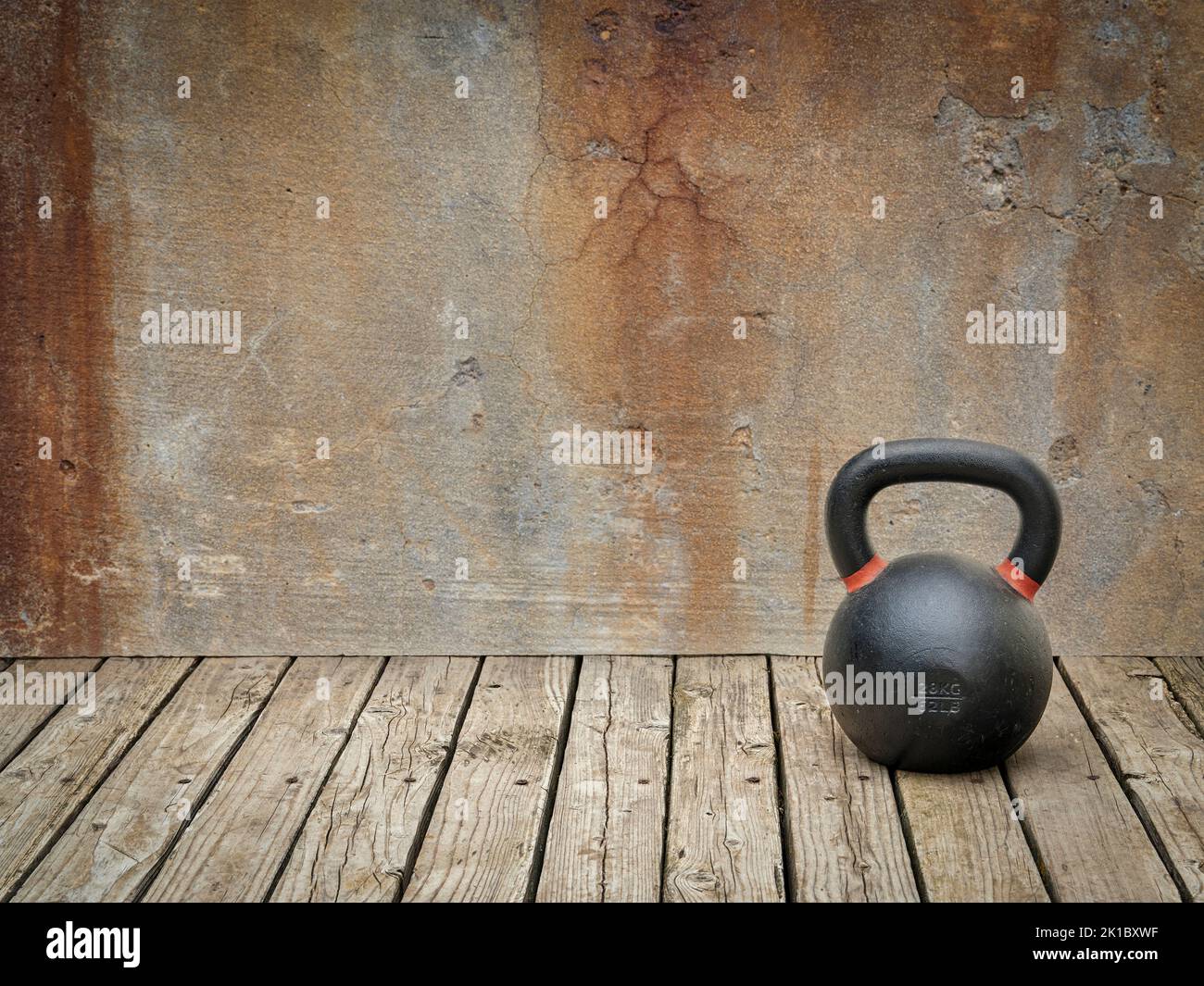iron kettlebell on a rustic wood background against grunge wall with a copy space Stock Photo