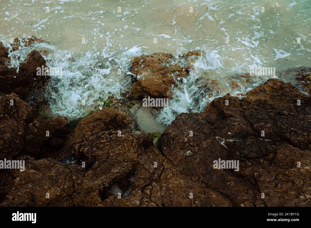 A top view of waves crashing the rocky beach in the daylight - great ...