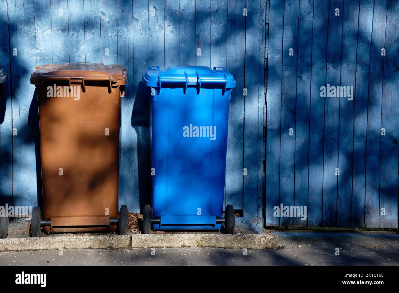 Wheelie bin colour blue, purple and black for refuge collection outside house in a row Stock Photo