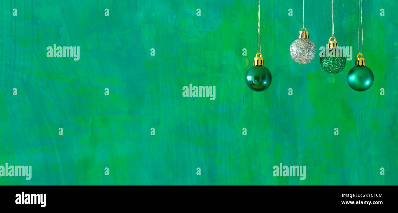 Green christmas balls and a silver one on green background.Christmas template with large copy space.Negative space technique. Stock Photo