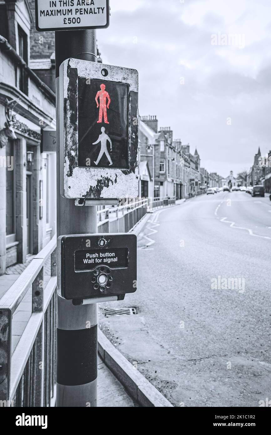 A vertical shot of a crosswalk sign with a button and a penalty for jaywalking in Thurso, Scotland on a gloomy winter day Stock Photo