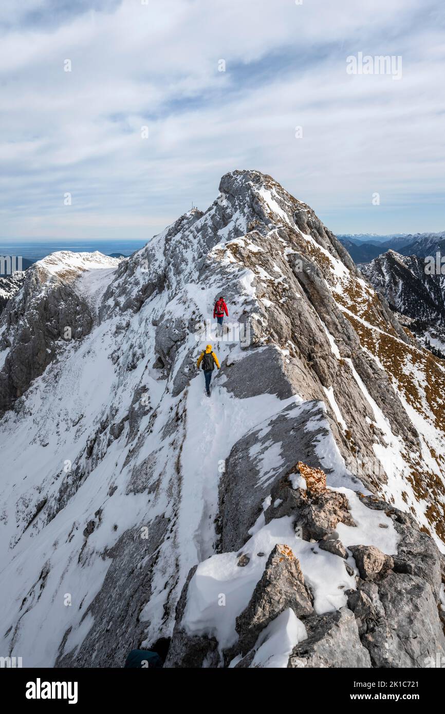 Two mountaineers on a rocky snowy ridge, hiking trail to Ammergauer Hochplatte, view of mountain panorama, behind summit Ammergauer Hochplatte, in Stock Photo