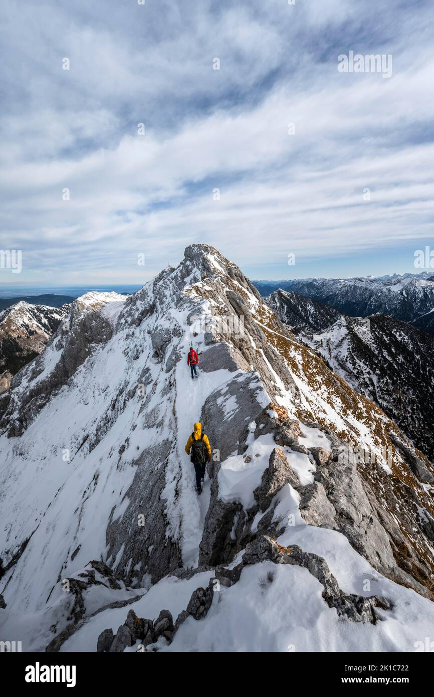 Two mountaineers on a rocky snowy ridge, hiking trail to Ammergauer Hochplatte, view of mountain panorama, behind summit Ammergauer Hochplatte, in Stock Photo