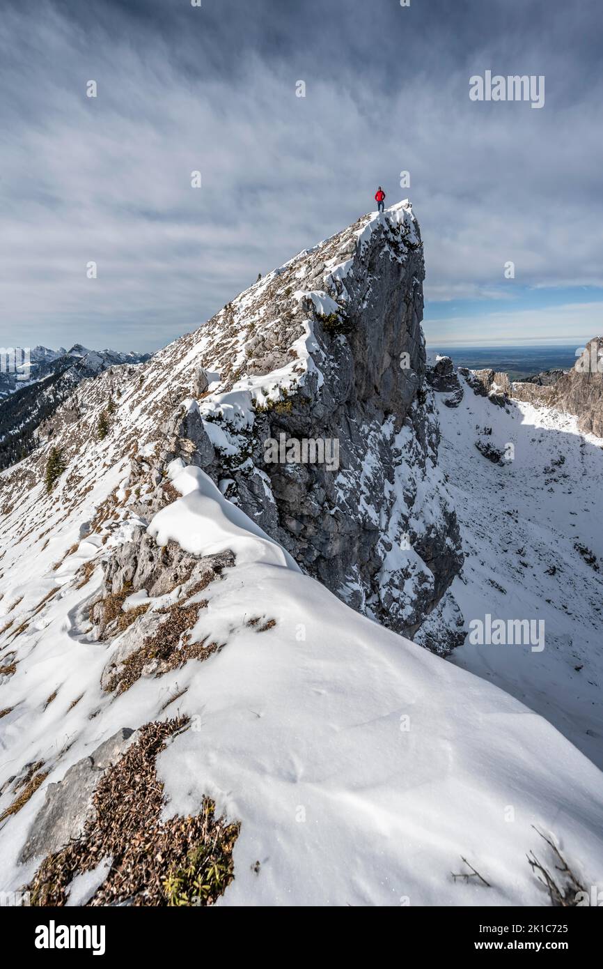 Mountaineer standing on a snowy rocky ridge, Fensterl on the hiking trail to Ammergauer Hochplatte, in autumn, Ammergau Alps, Bavaria, Germany Stock Photo