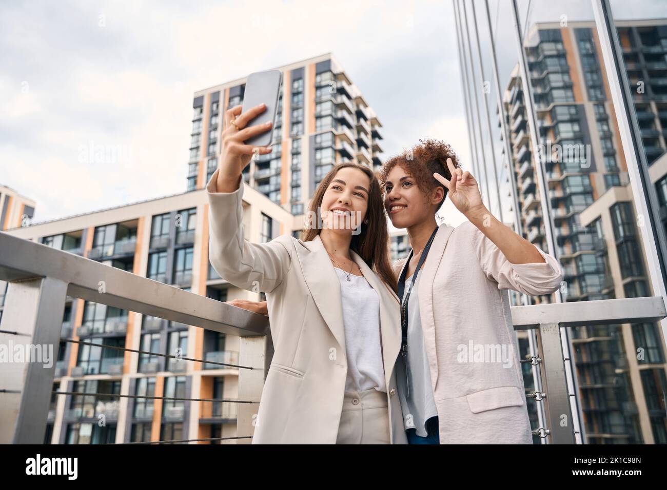 joyful-office-employees-taking-selfies-on-outdoor-balcony-stock-photo