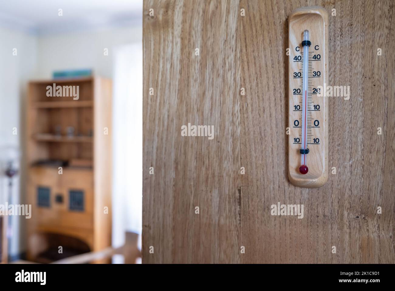 Mercury thermometer for determining the temperature indoors, hanging on a wooden wall. Stock Photo