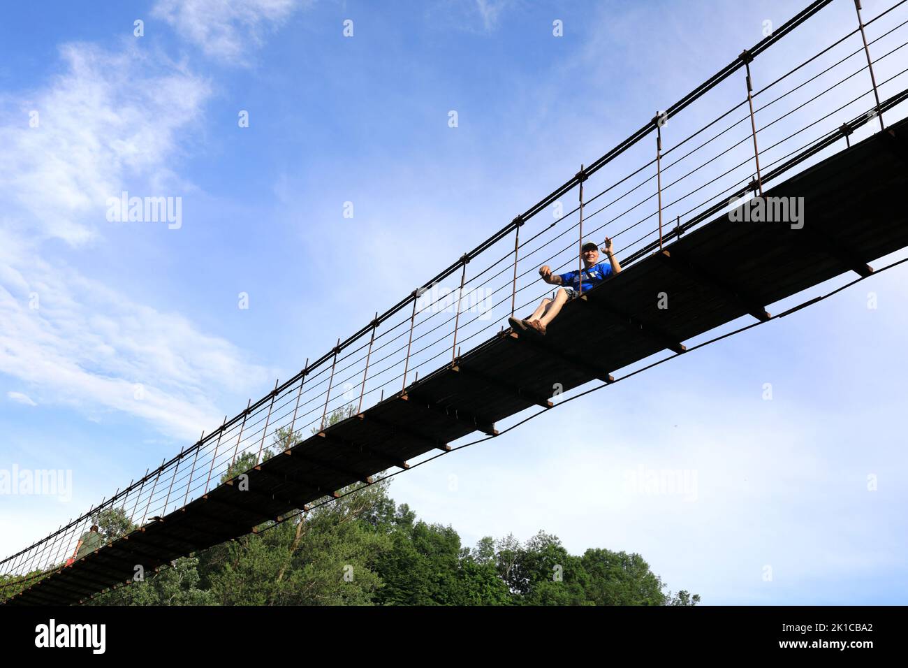 Man sitting on suspension bridge over Belaya River, Adygea Stock Photo ...
