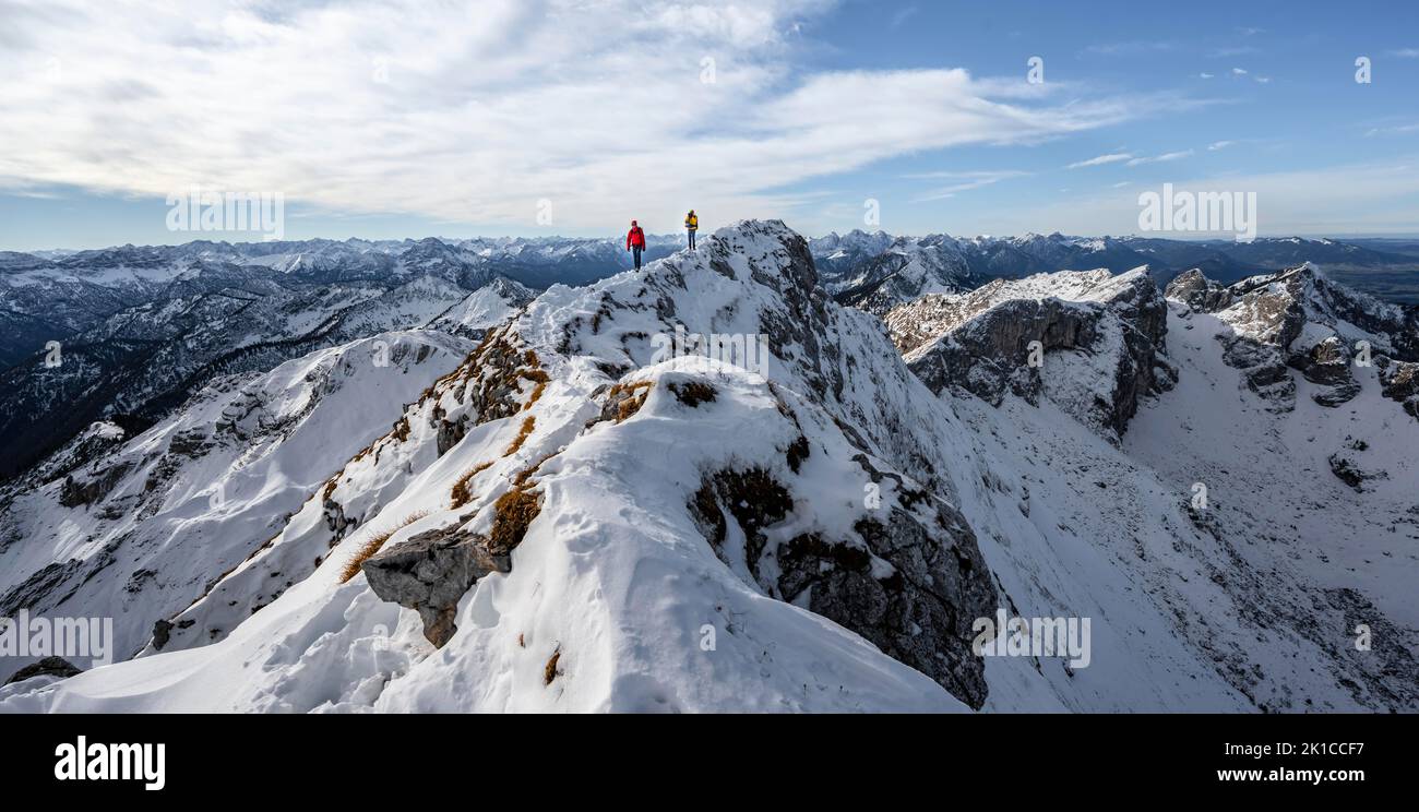 Two mountaineers on a narrow rocky snowy ridge, behind peak crow, view of mountain panorama, hiking to Ammergauer Hochplatte, in autumn, Ammergau Stock Photo