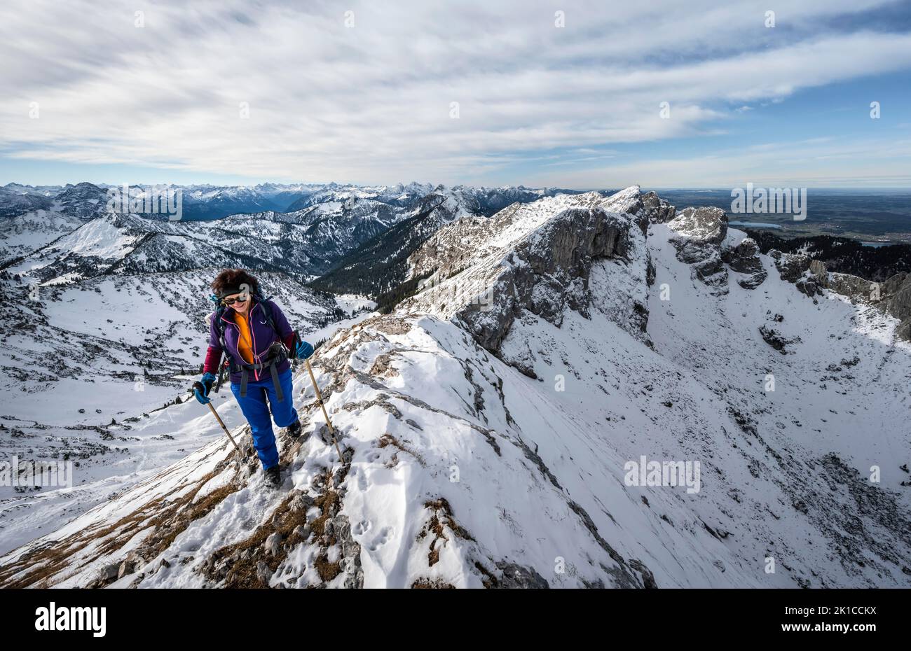 Climber on a rocky snowy ridge, hiking trail to Ammergauer Hochplatte, view of mountain panorama, behind peak crow, in autumn, Ammergau Alps Stock Photo