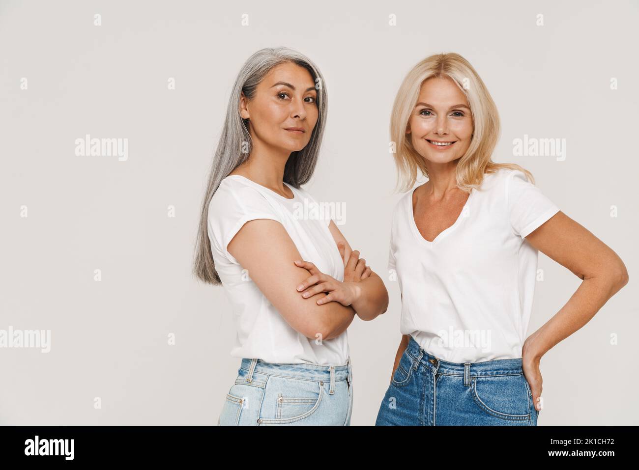 Mature multiracial women with gray hair wearing t-shirts posing at camera isolated over white background Stock Photo
