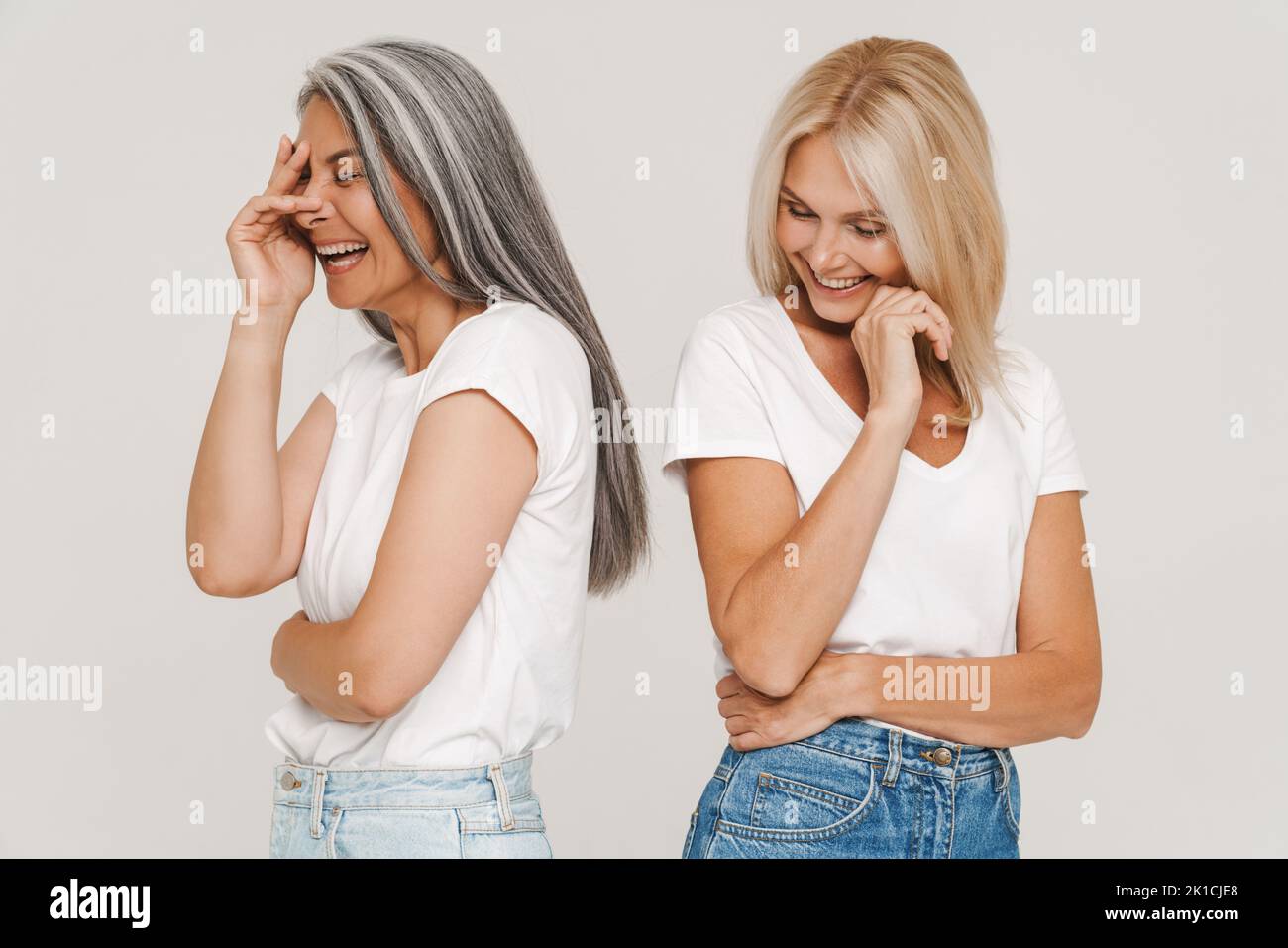 Mature multiracial women with gray hair wearing t-shirts laughing at camera isolated over white background Stock Photo