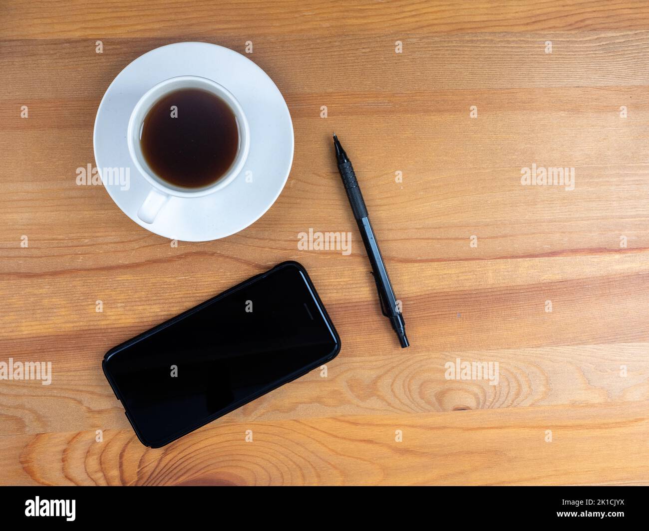 lifestyle morning coffee cell phone and pen on a wooden desk Stock Photo