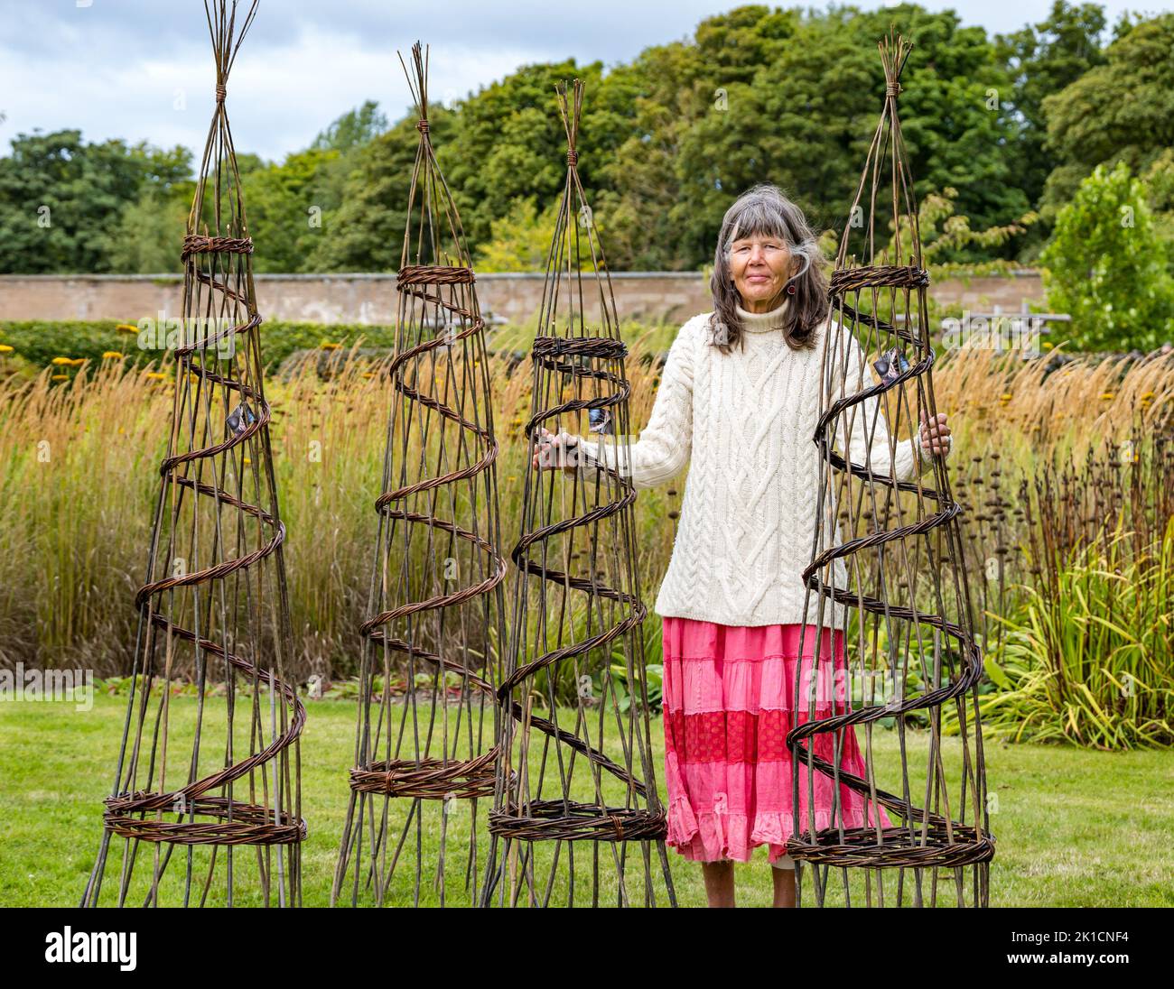 Amisfield Walled Garden, East Lothian, Scotland, UK, 17th September 2022. Art in the Garden: an exhibition of artwork by artists with differing styles and materials takes place for a week. Pictured: weaver Lise Bech with some of her woven willow obelisk work. Credit: Sally Anderson/Alamy Live News Stock Photo