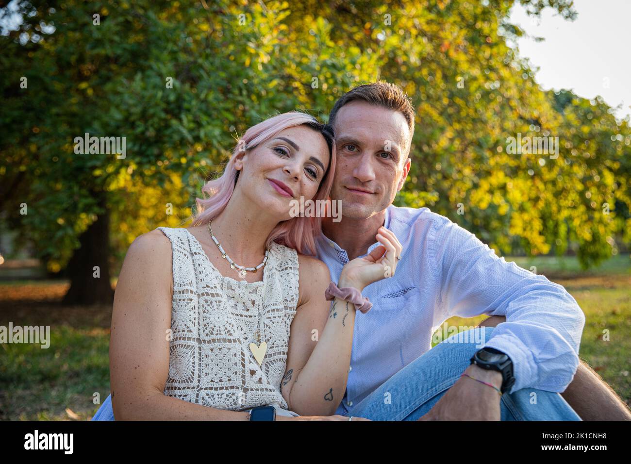 A loving couple sitting together in a park in the open air, partners enjoying their time together. Stock Photo