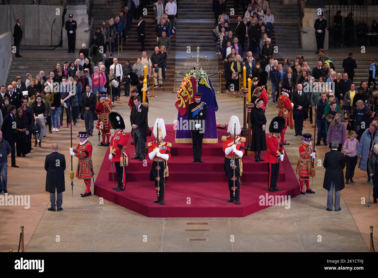Members of the public file past as Queen Elizabeth II 's grandchildren (clockwise from front centre) the Prince of Wales, Peter Phillips, James, Viscount Severn, Princess Eugenie, the Duke of Sussex, Princess Beatrice, Lady Louise Windsor and Zara Tindall hold a vigil beside the coffin of their grandmother as it lies in state on the catafalque in Westminster Hall, at the Palace of Westminster, London. Picture date: Saturday September 17, 2022. Stock Photo