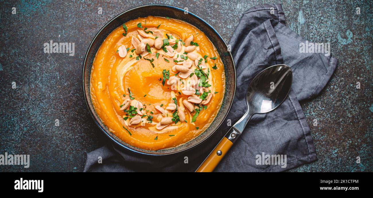 Bowl with pumpkin cream soup with peanuts on dark stone background Stock Photo