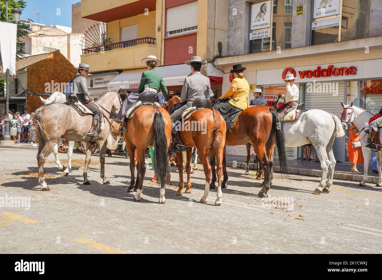 Men and women in traditional spanish costumes horseback riding during