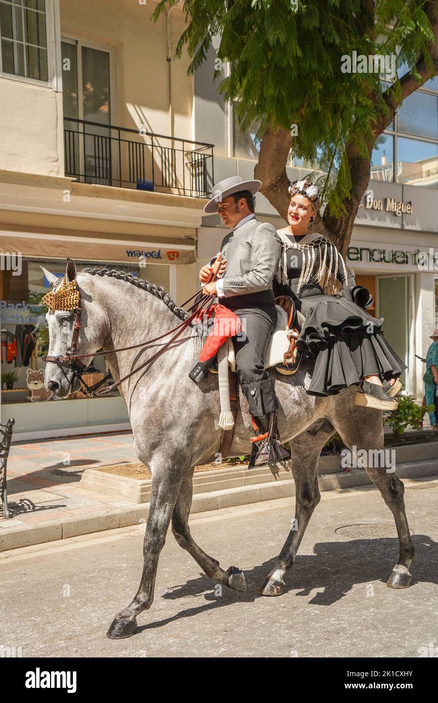 Men and women in traditional spanish costumes horseback riding during