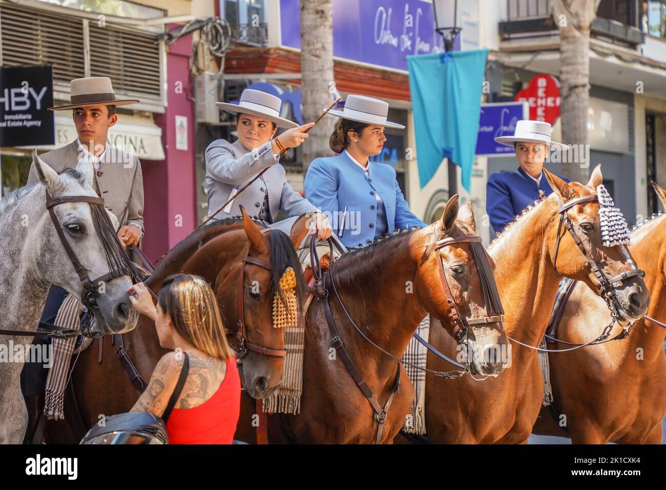 Men and women in traditional spanish costumes horseback riding during