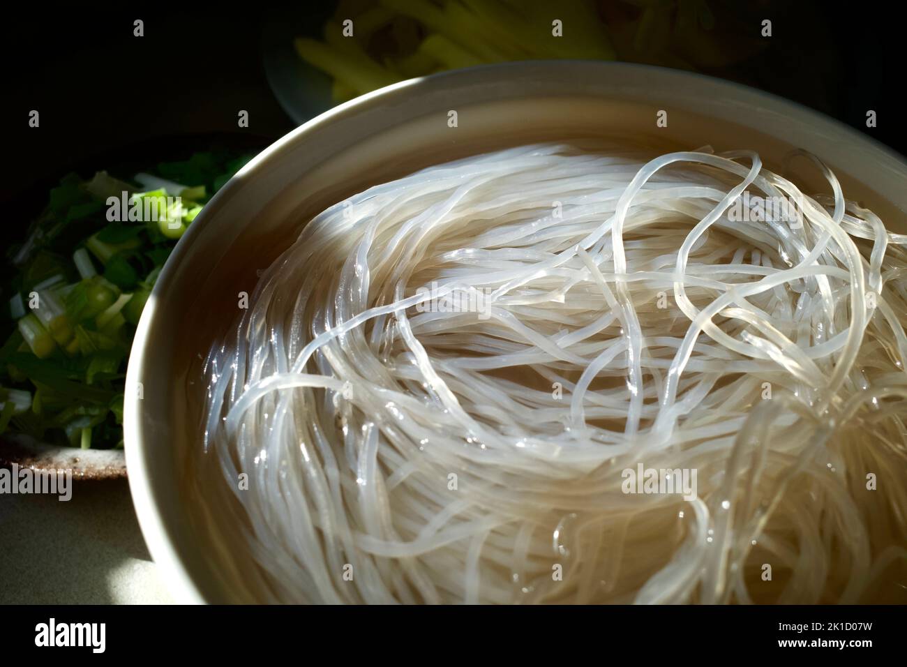 Glass noodles soaked in water. The photo was taken under natural light on a kitchen worktop. Stock Photo