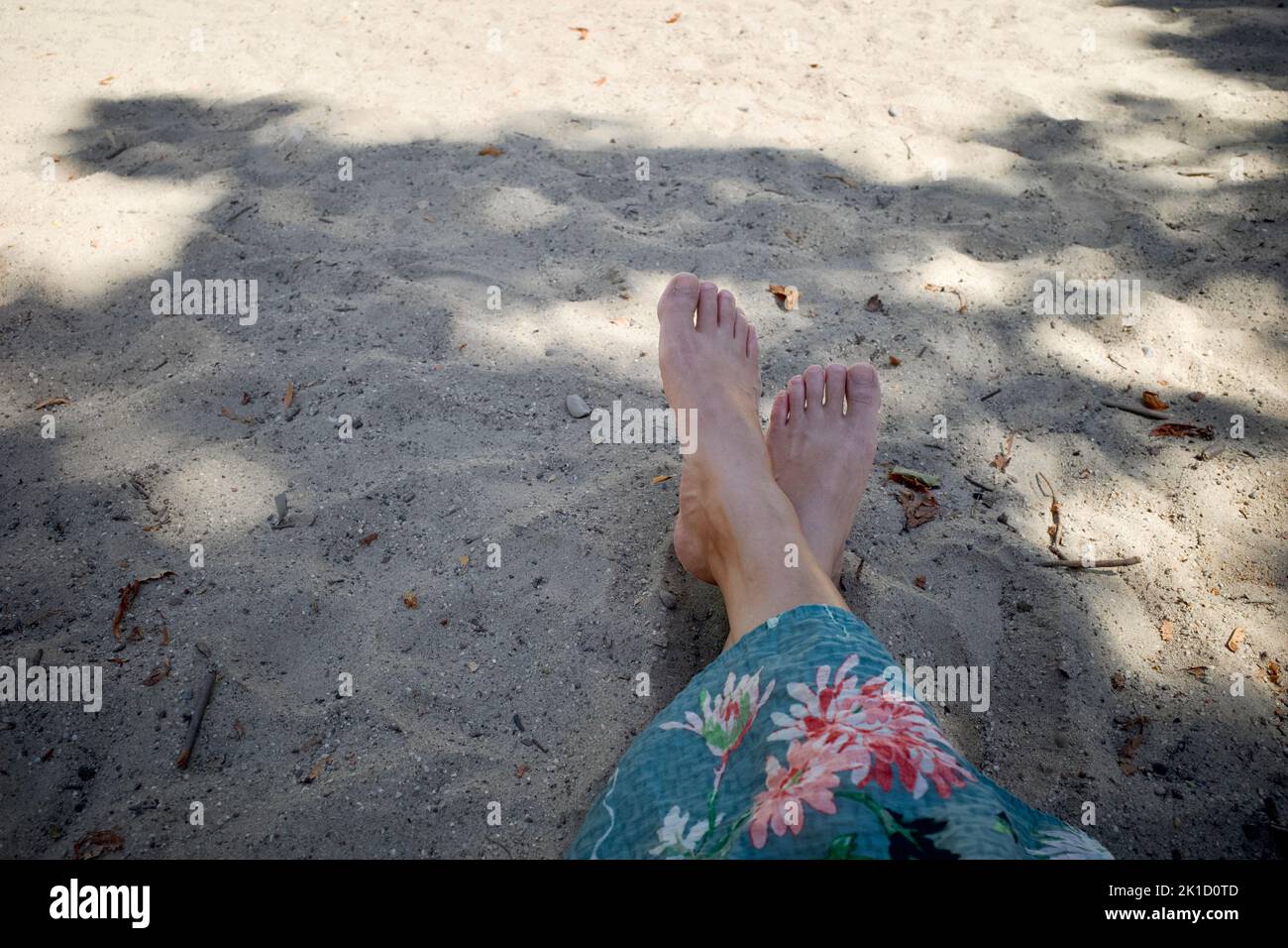 Feet of a woman on the sand in summer. It was a relaxing and sunny weekend. She sat in the shade. Stock Photo