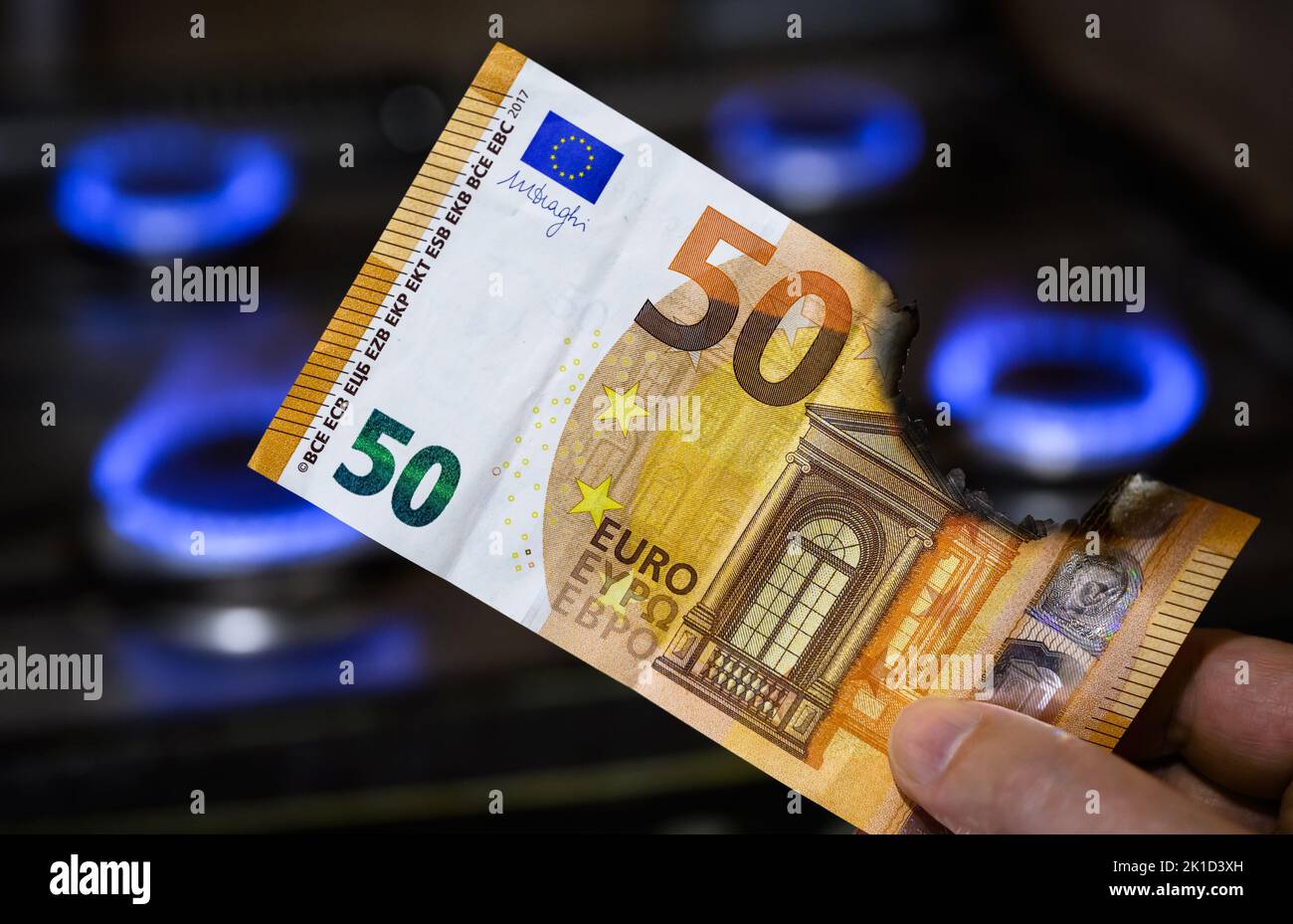 Euro money and gas burners, burnt EU banknote is by gas stove, European currency near blue propane flame. Concept of energy crisis in Europe, Gazprom, Stock Photo