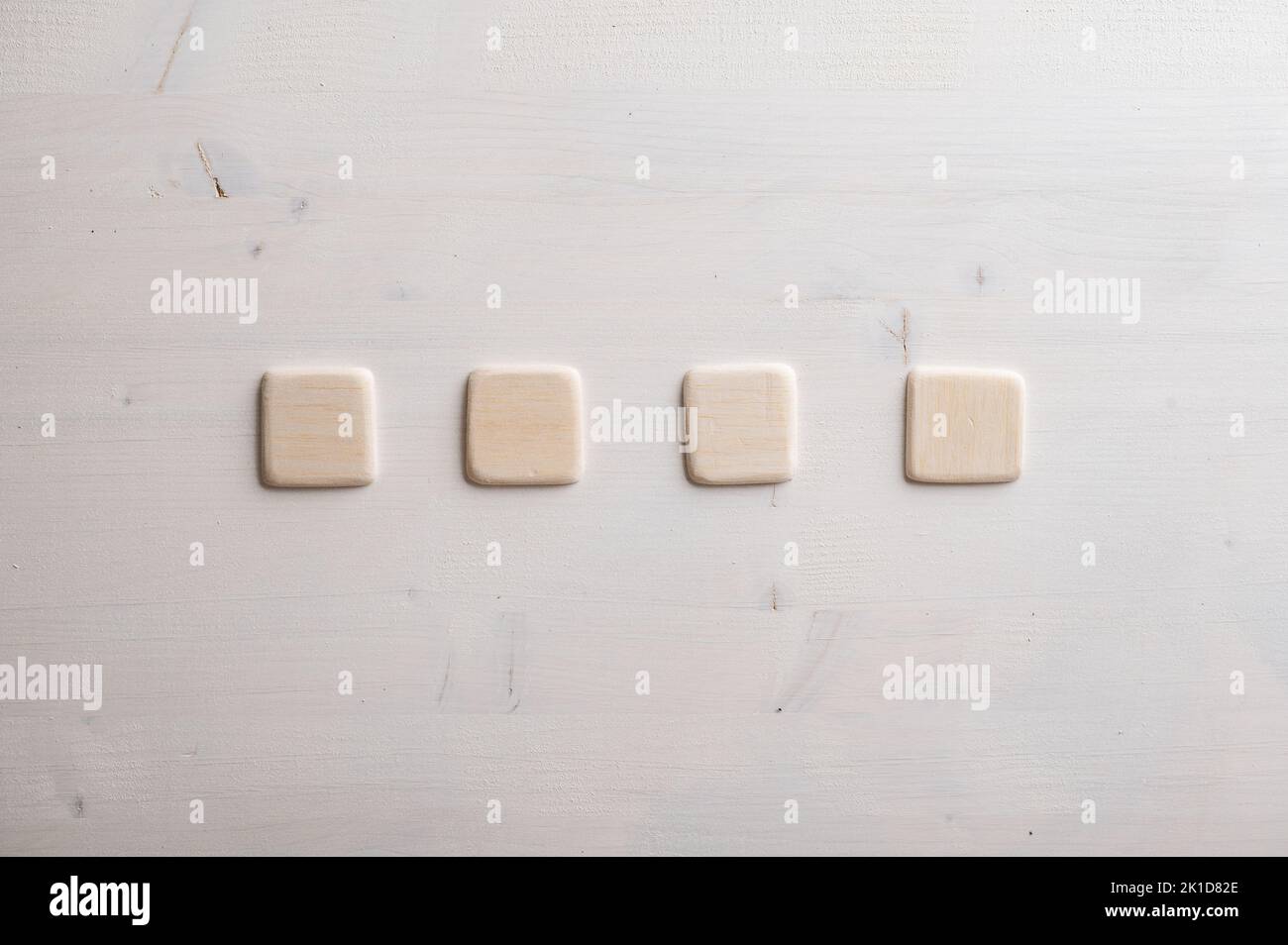 Four blank wooden squares placed in a row over wooden background. Stock Photo