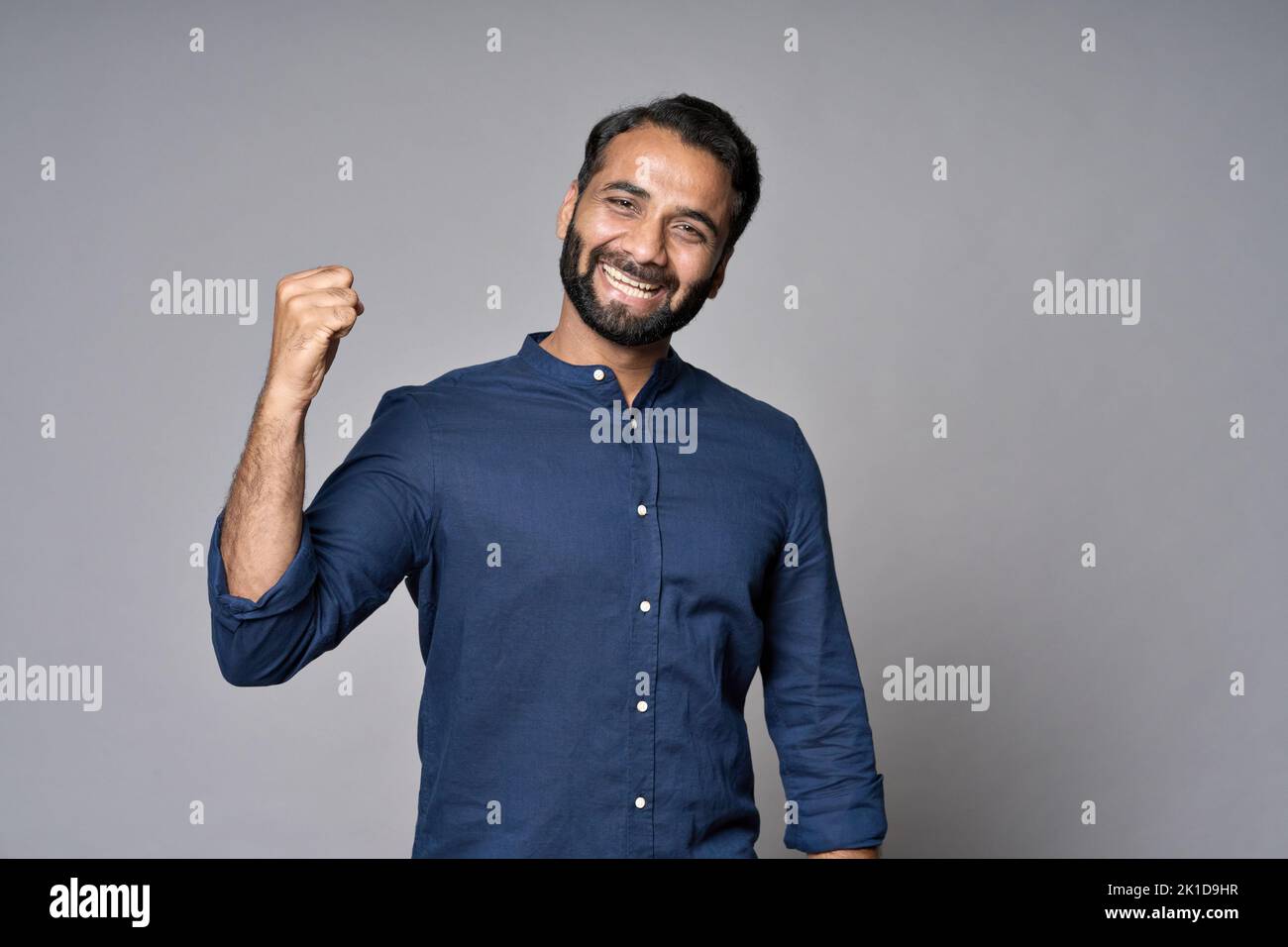 Happy rich indian businessman investor raising fist isolated on gray background. Stock Photo
