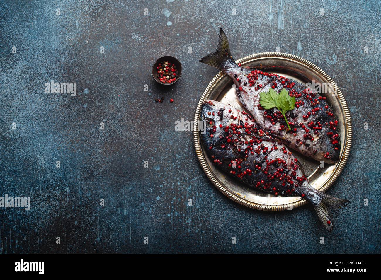 Raw fish dorado with pink peppercorn for healthy cooking top view Stock Photo