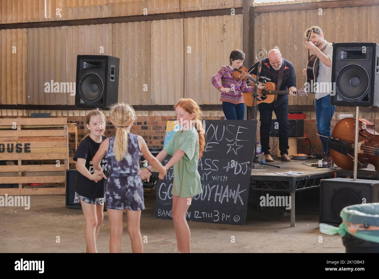 East Neuk, UK - August 14, 2022: Children dance and locals enjoy a live band performing country folk music in a barn at Bowhouse Farmer's Market in Ea Stock Photo