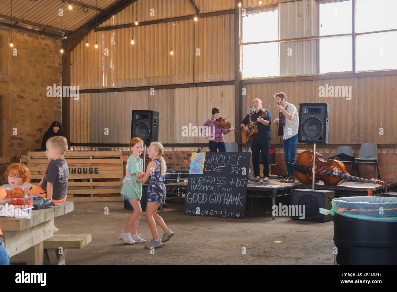 East Neuk, UK - August 14, 2022: Children dance and locals enjoy a live band performing country folk music in a barn at Bowhouse Farmer's Market in Ea Stock Photo