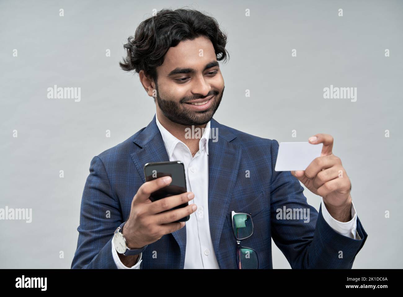 Happy indian arab business man using phone holding credit card. Stock Photo