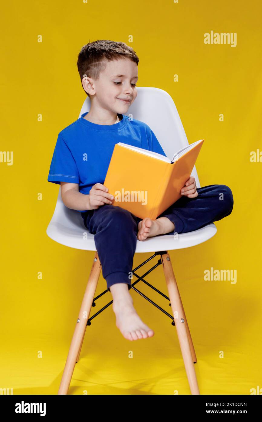 Little cheerful blond green-eyed boy 5-6 years old in a stylish blue T ...