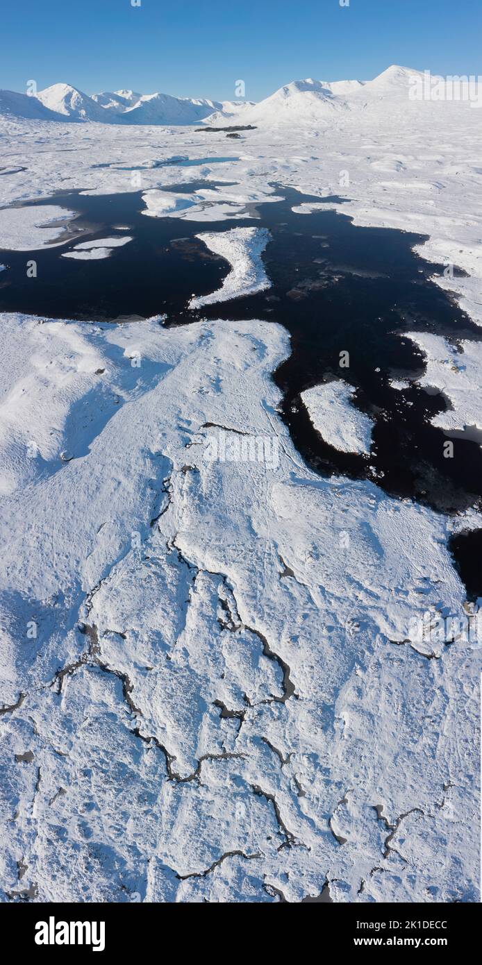 Beautiful aerial drone Winter landscape images of Loch Ba and snow covered mountains in background in Scottish Highlands on blue sky Winter day Stock Photo