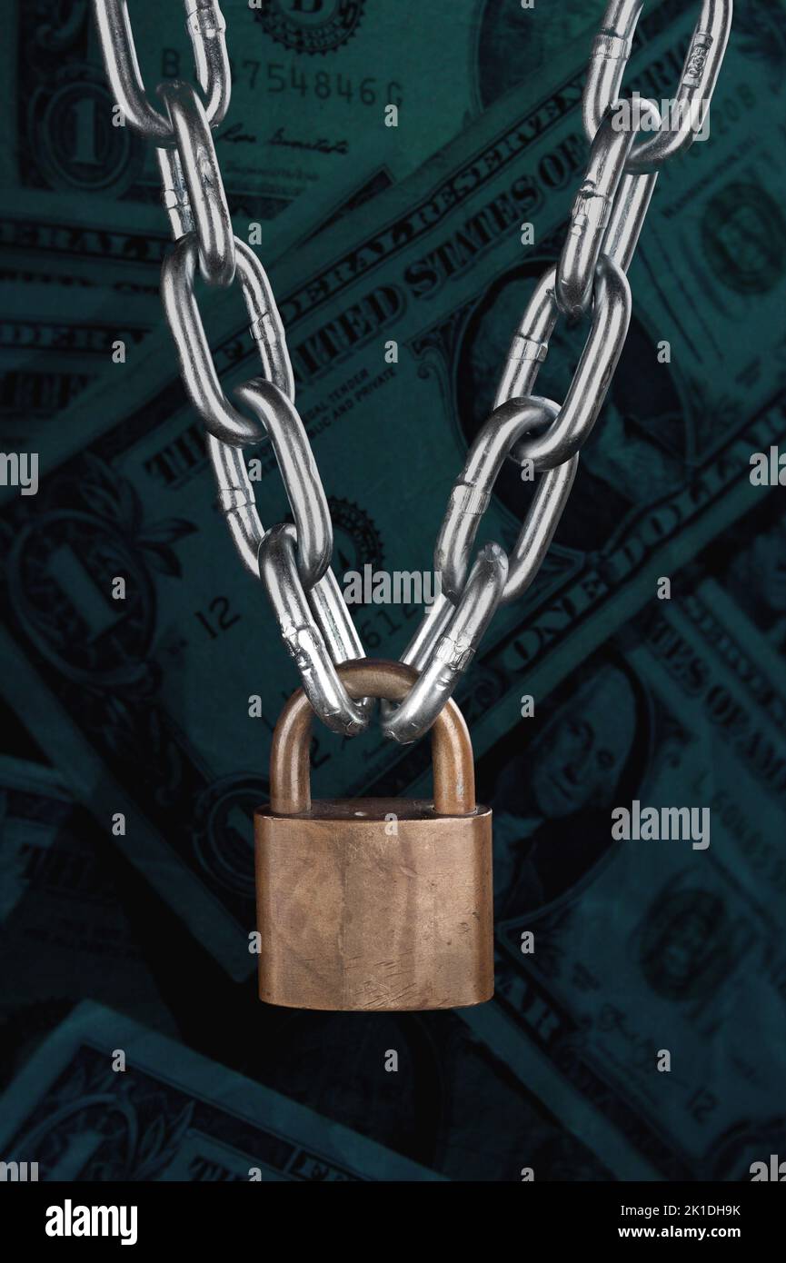 A vintage brass lock connecting a thick, chrome chain isolated on black. Stock Photo