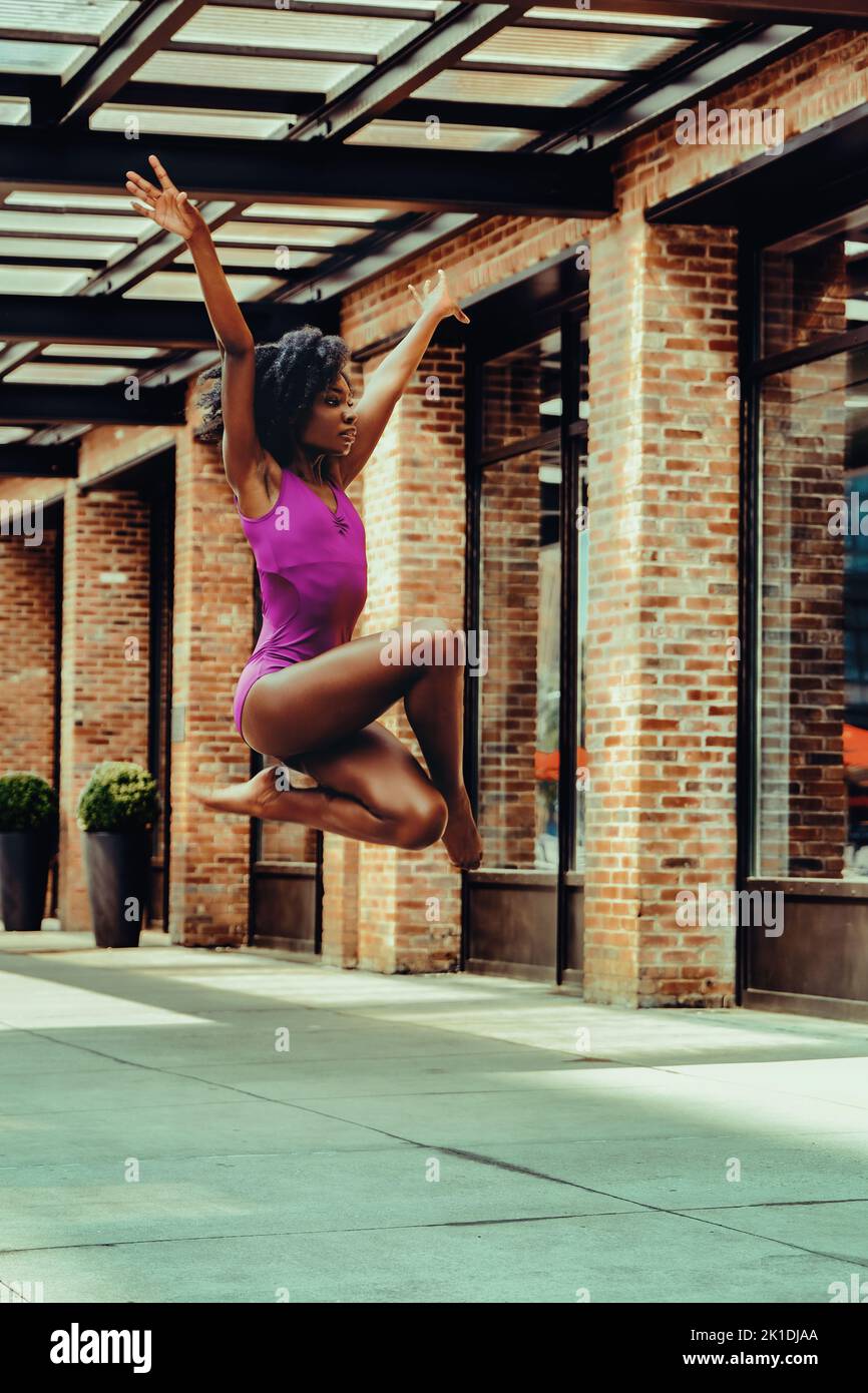ballerina modern dancer in leotard outdoors in urban street sidewalk brick wall Stock Photo