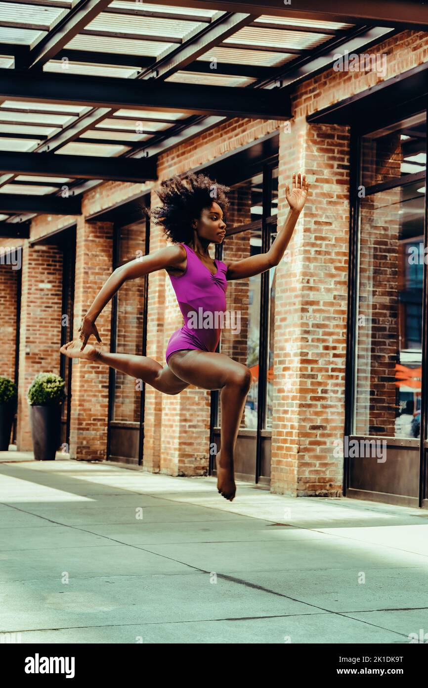 ballerina modern dancer in leotard outdoors in urban street sidewalk brick wall Stock Photo