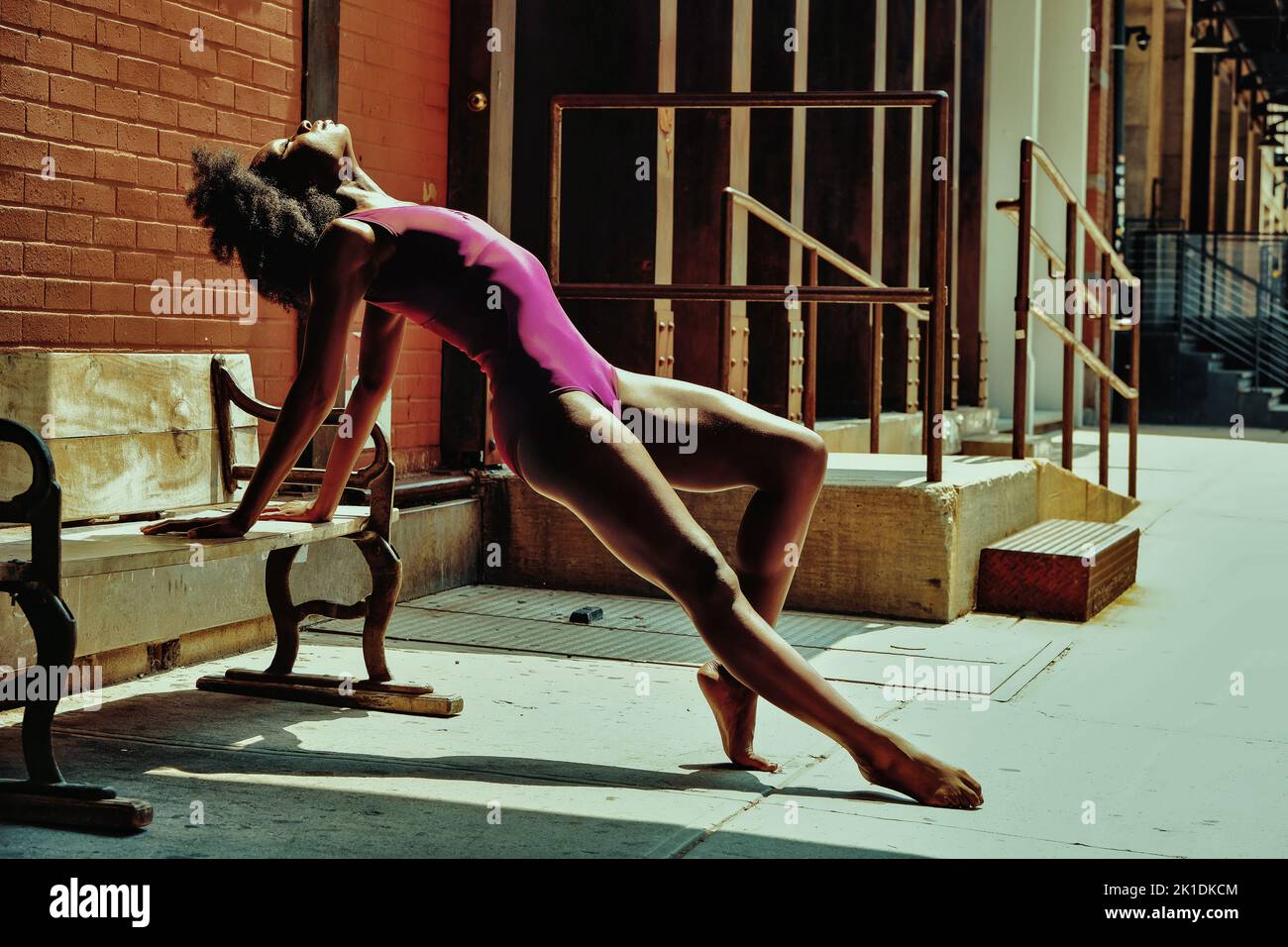 ballerina modern dancer outdoors stretching on a bench Stock Photo